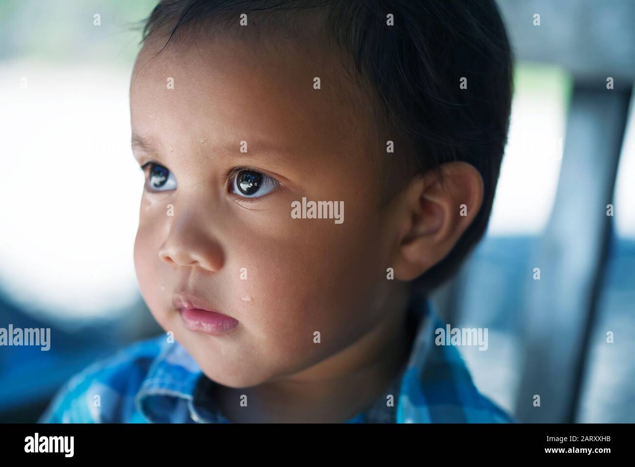 Un niño pequeño de unos dos años de edad que se ve triste, con ojos de lágrimas y considerado; después de llorar. Foto de stock