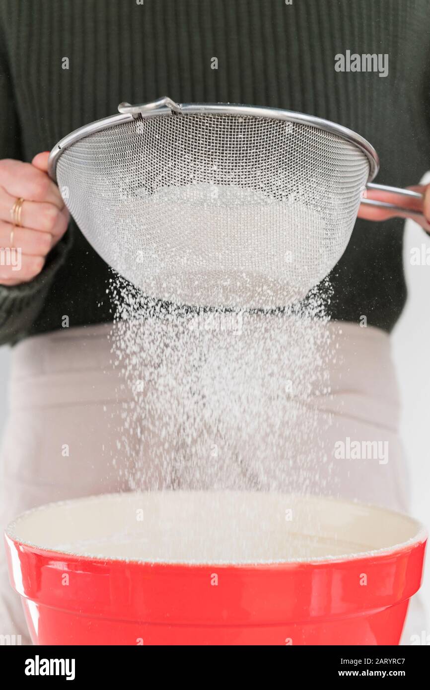 Mujer tamizando la harina en el tazón Foto de stock