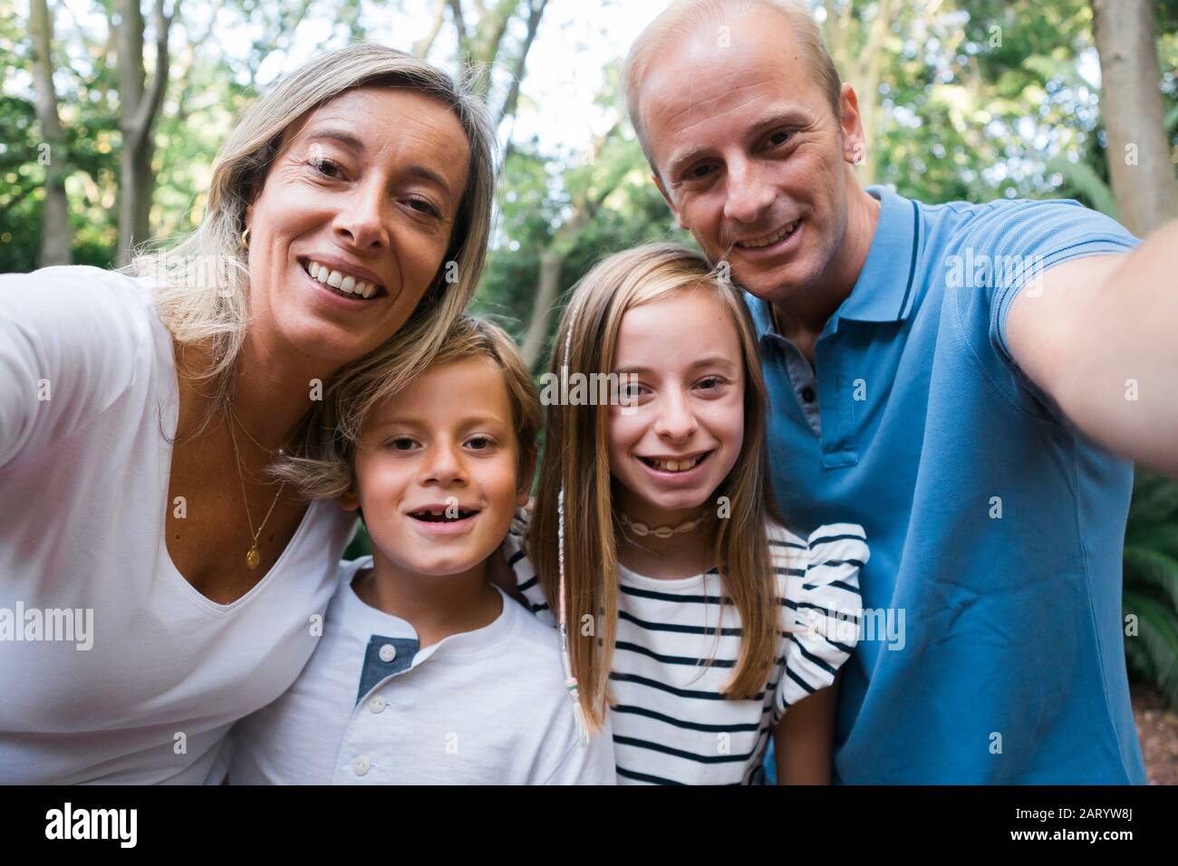 Familia tomando selfie por los árboles Foto de stock