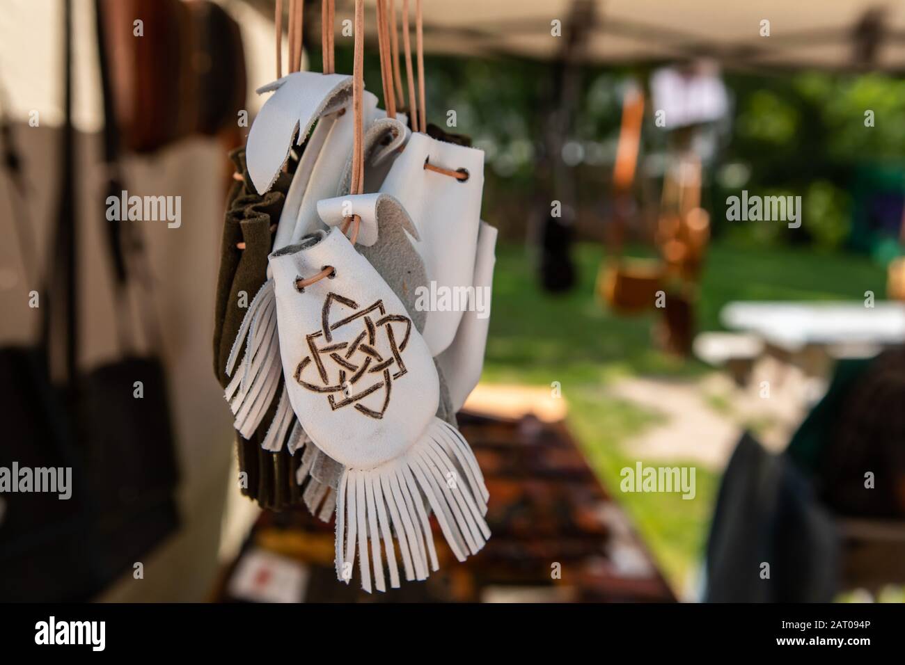 Artículos de cuero hechos a mano a la venta en una tienda de artesanía en  el mercado local del agricultor. Primer plano de bolsas o carteras blancas  y pequeñas con flecos y