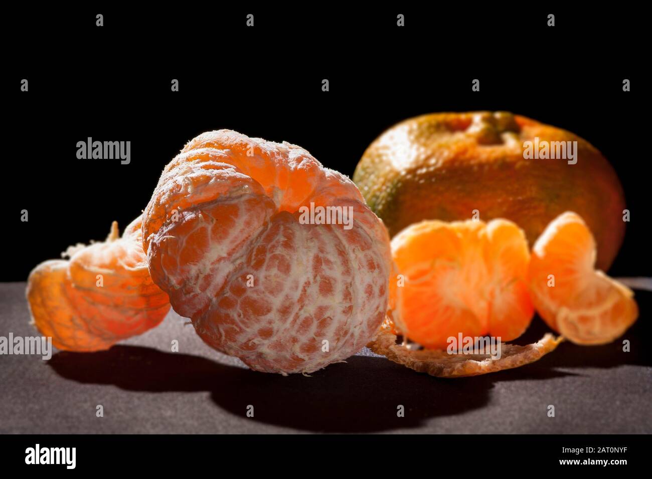 naranjas mandarina, cítricos reticula.on mesa con fondo negro y luz de espalda vida fija .mandarina variedad naranja contiene pomelo y c vitamina. Foto de stock