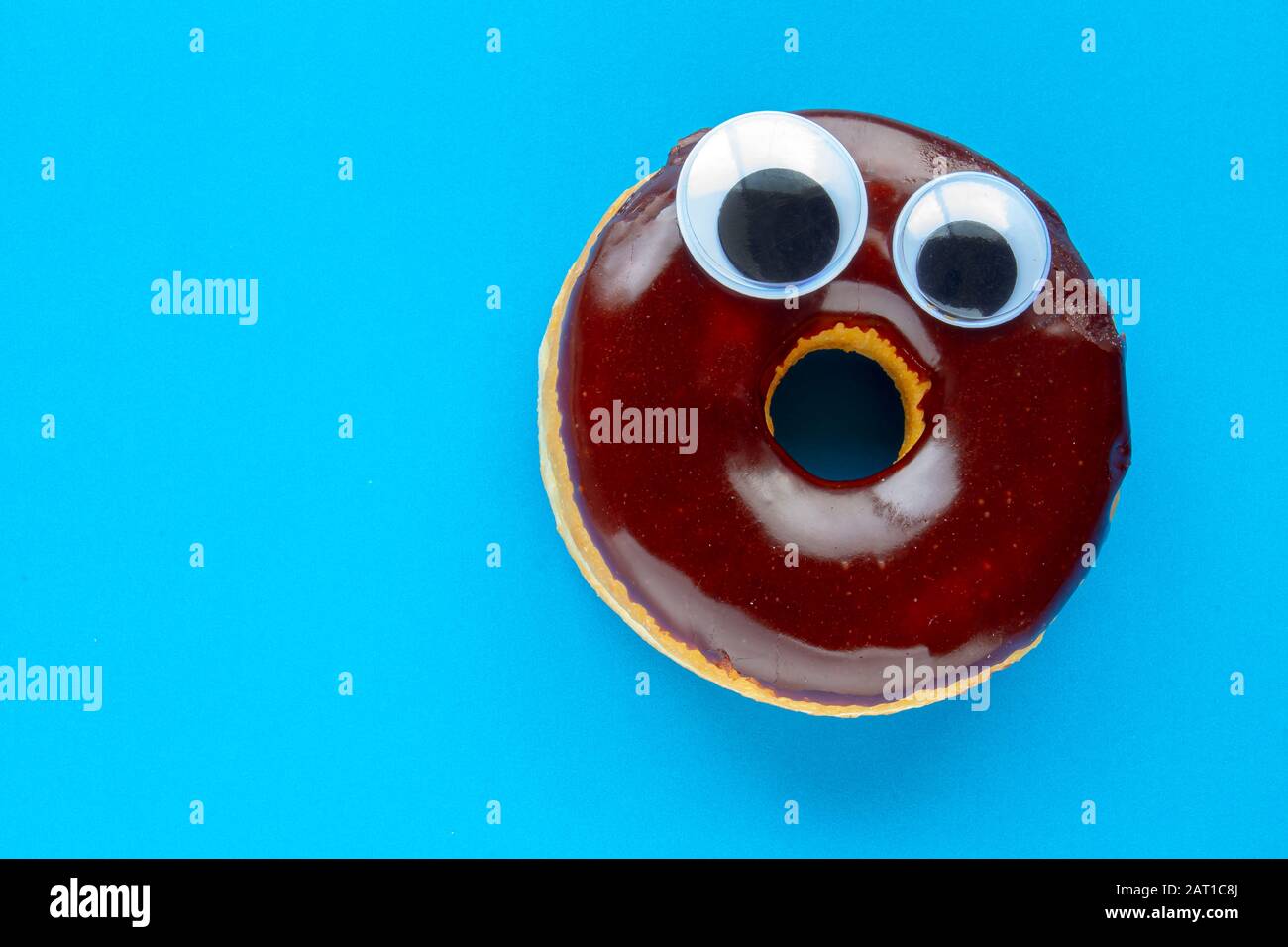 Un donut De Chocolate Tim Hortons con Bolas De Ojo de gorgojo negro sobre fondo azul Foto de stock
