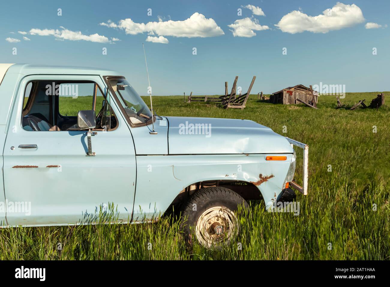 Camión azul en un campo abierto con viejo establo y cielo azul nube fondo Foto de stock