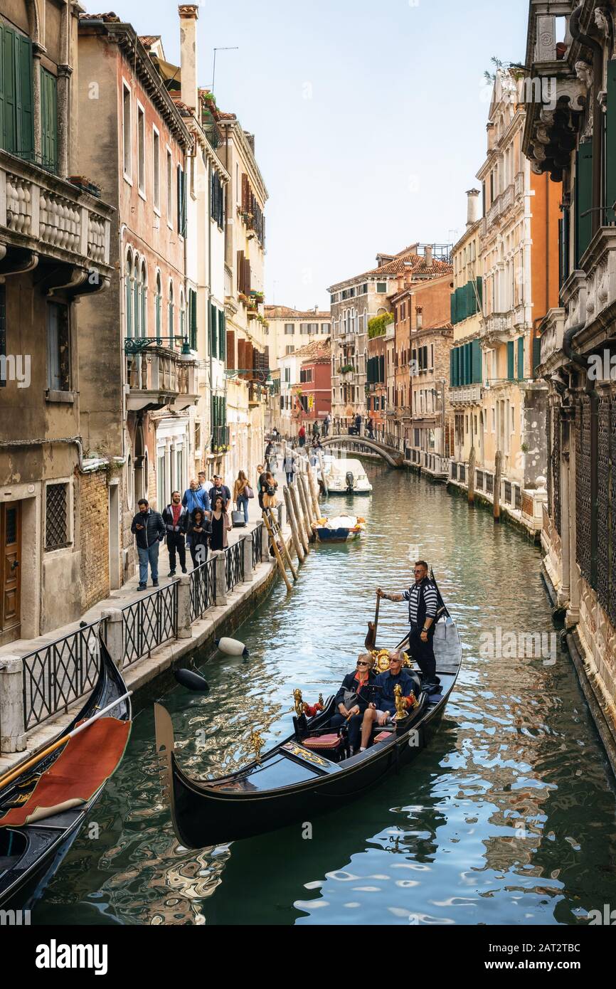Venecia, Italia - 9 de mayo de 2019: gondolero veneciano punts góndola por las aguas del canal estrecho de Venecia Italia Foto de stock