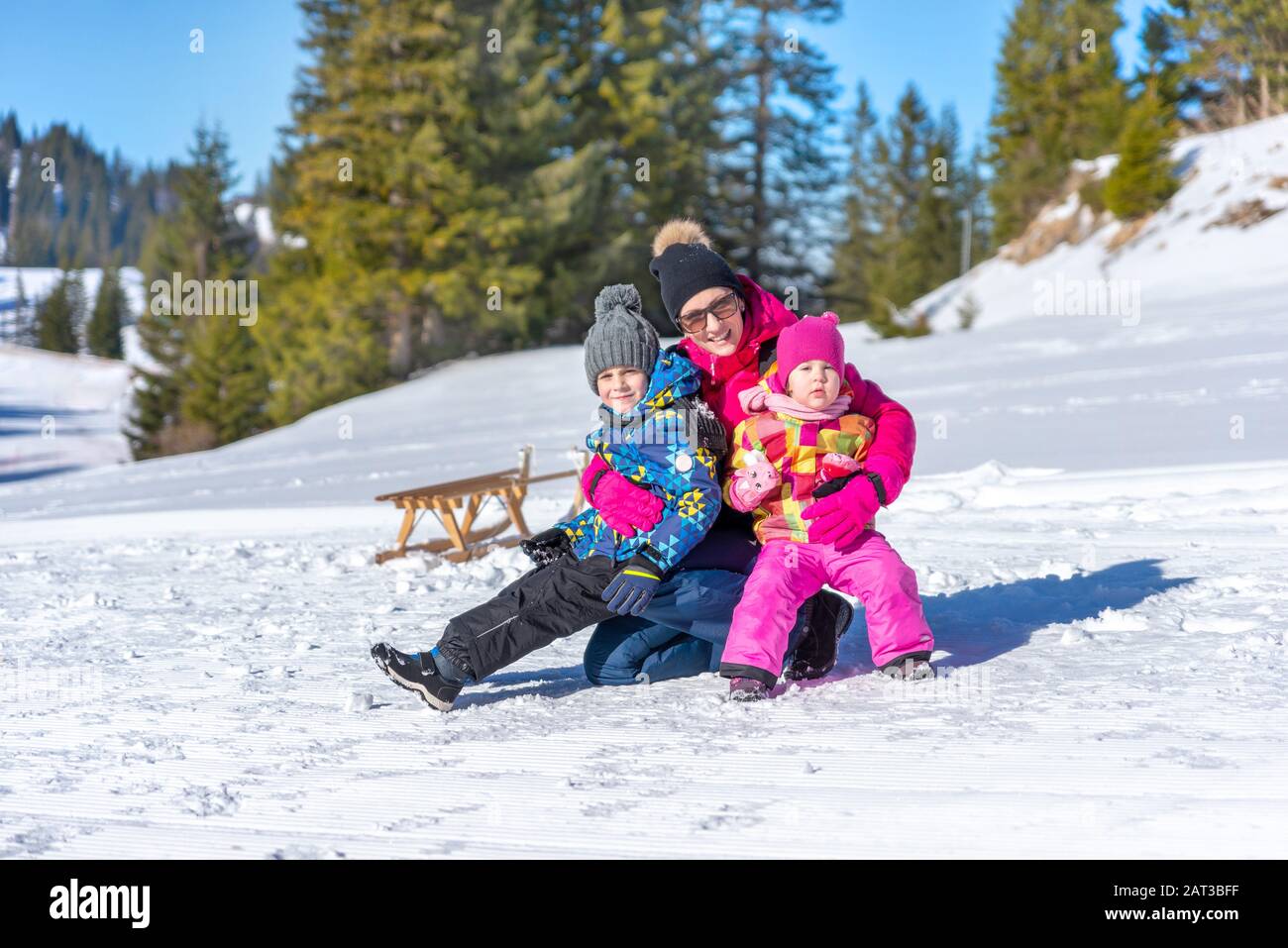 La madre sostiene a los niños en sus brazos sobre la nieve. Concepto de unas vacaciones de invierno y una familia feliz Foto de stock
