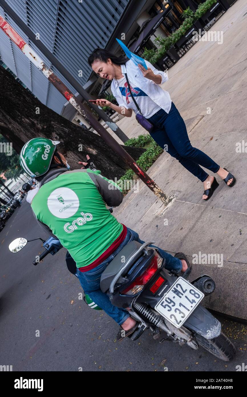 Mujeres jóvenes que utilizan un taxi Grab a través de la aplicación móvil, Ciudad Ho Chi Minh, Vietnam Foto de stock