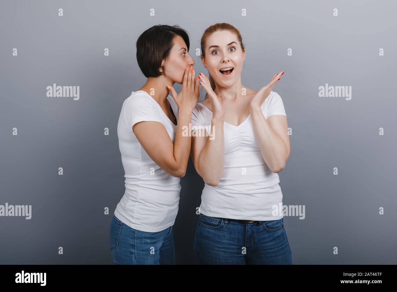 Mujeres que dicen un secreto a su amiga. Maravilla emoción en cara-Imagen Foto de stock