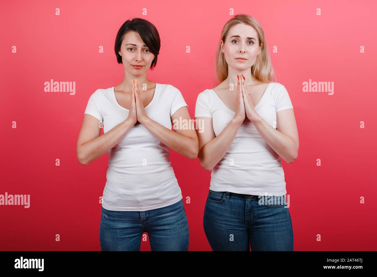 Dos mujeres hacen un gesto de súplica mirando la cámara.- Imagen Foto de stock