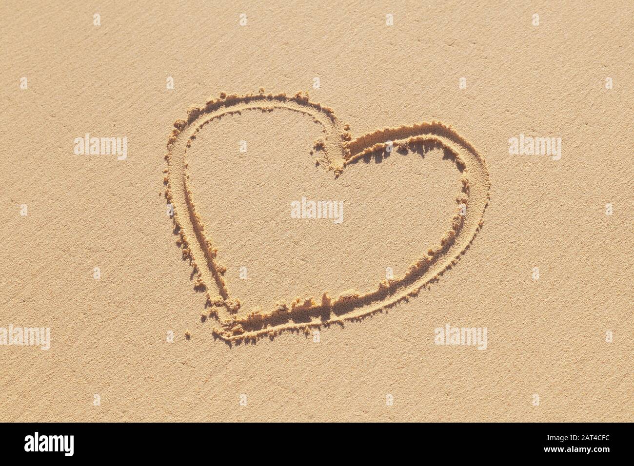 El signo de corazón dibujado a mano está en una arena costera, una metáfora romántica del día de fiesta Foto de stock