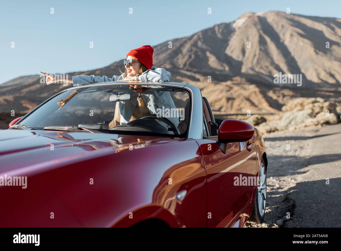 Retrato de estilo de vida de una joven que disfruta de un viaje por carretera en el valle del desierto, saliendo del coche convertible en la carretera Foto de stock