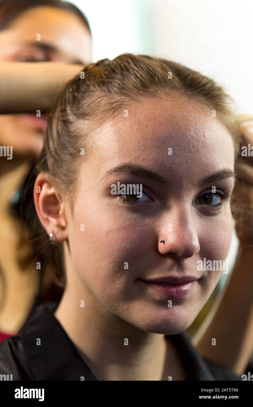 Cara de la joven mujer caucásica mirando a la cámara mientras que teniendo el pelo trenzado. Profundidad de campo poco profunda. Foto de stock