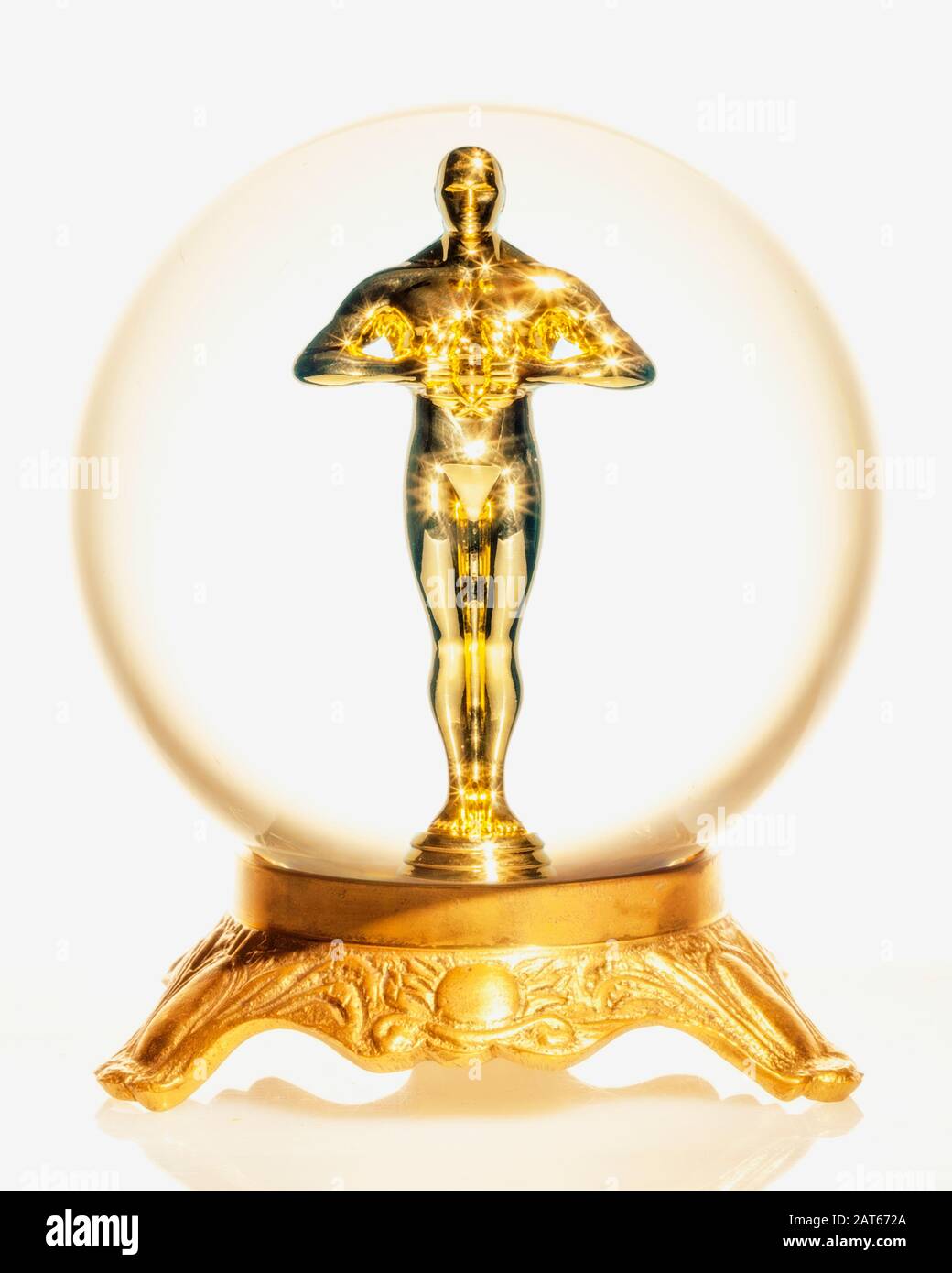 Una estatua de oro de estilo Oscar de un hombre parado dentro de una bola de cristal Foto de stock