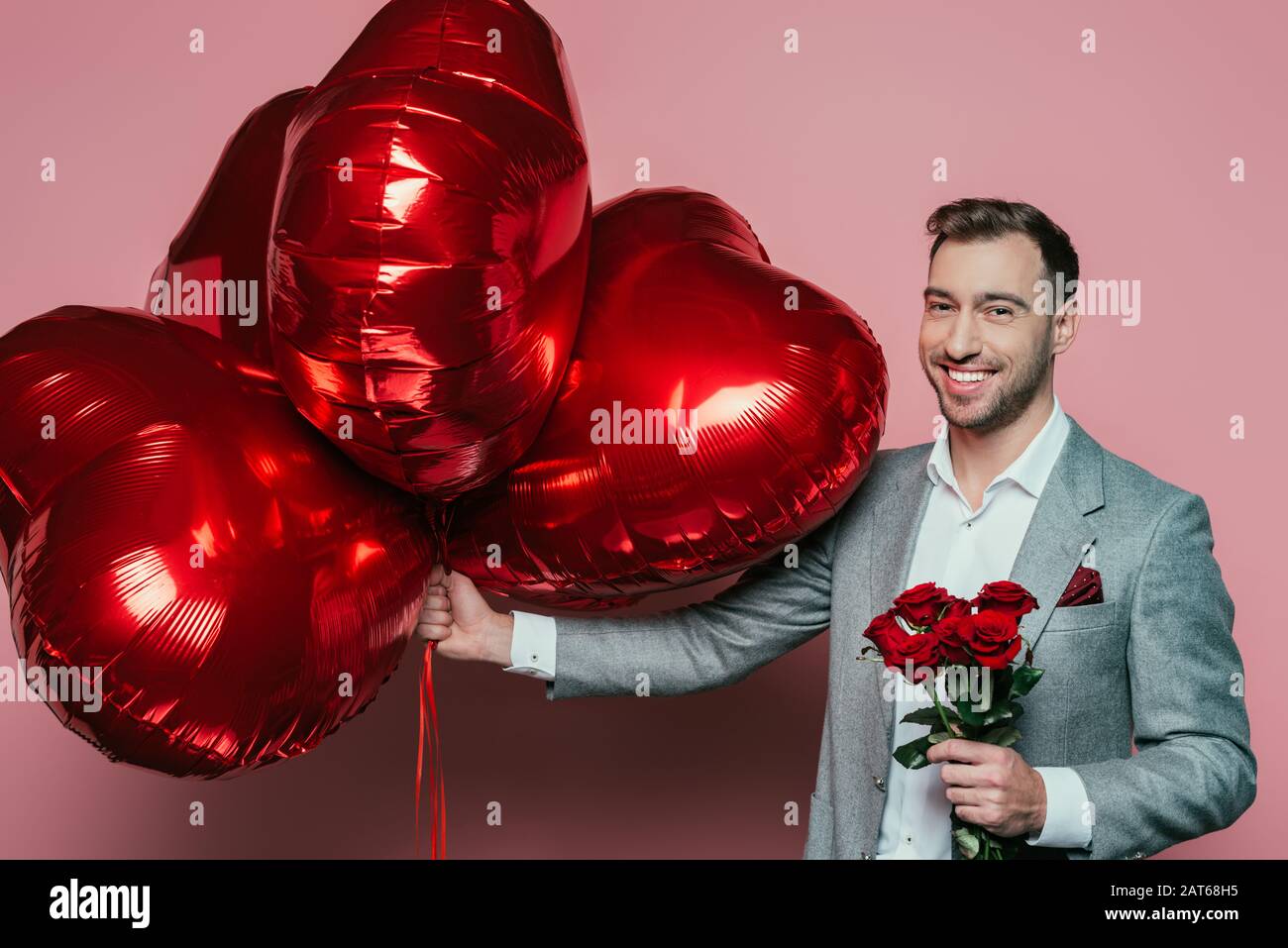 Día de San Valentín hombre sostiene flores en racimos de color rojo corazón  amor de fondo. Tarjeta de San Valentín Fotografía de stock - Alamy