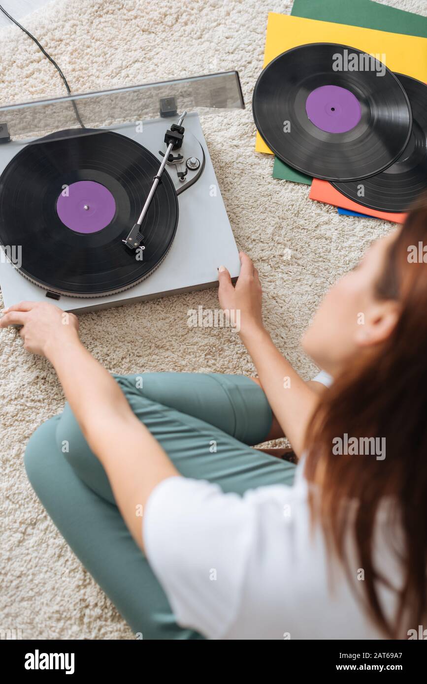 enfoque selectivo de reproductor de discos vintage cerca de la chica sentada en la alfombra Foto de stock