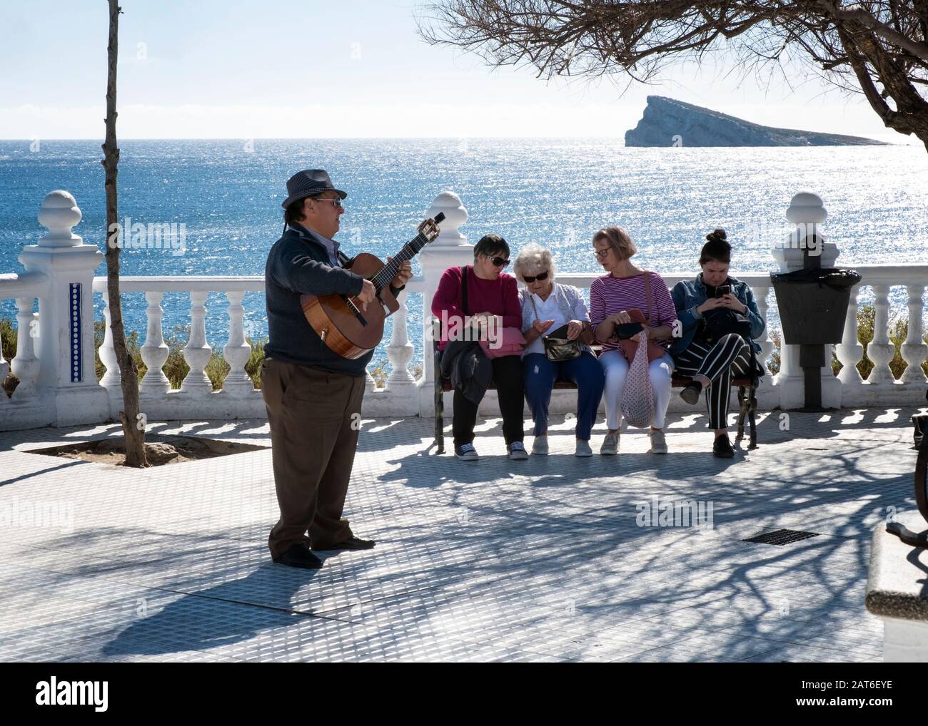 Guitarrista callejero actuando para turistas sentados en el Mirador del  Castell con la isla de Benidorm en la parte trasera (Costa Blanca,  Alicante, España Fotografía de stock - Alamy