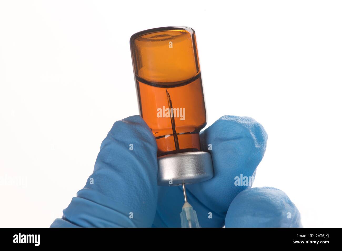 La jeringa extrae el medicamento líquido del vial de color ámbar en la mano enguantada de la enfermera. Foto de stock