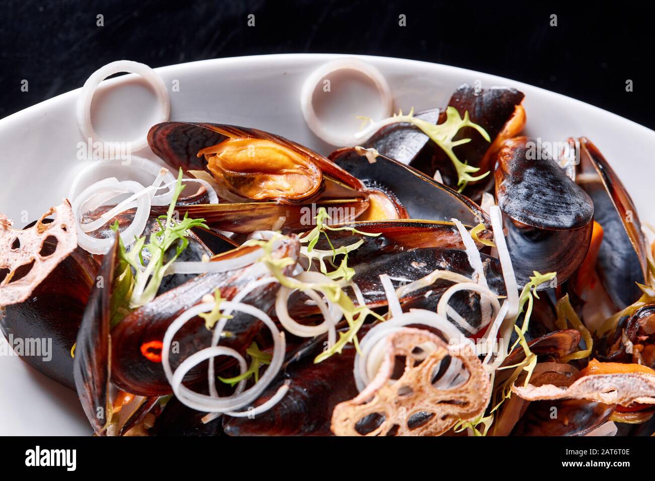 Deliciosos mejillones de marisco con rúcula y cebollas. Limón y baguette . Almejas en las conchas. Menú del restaurante Foto de stock