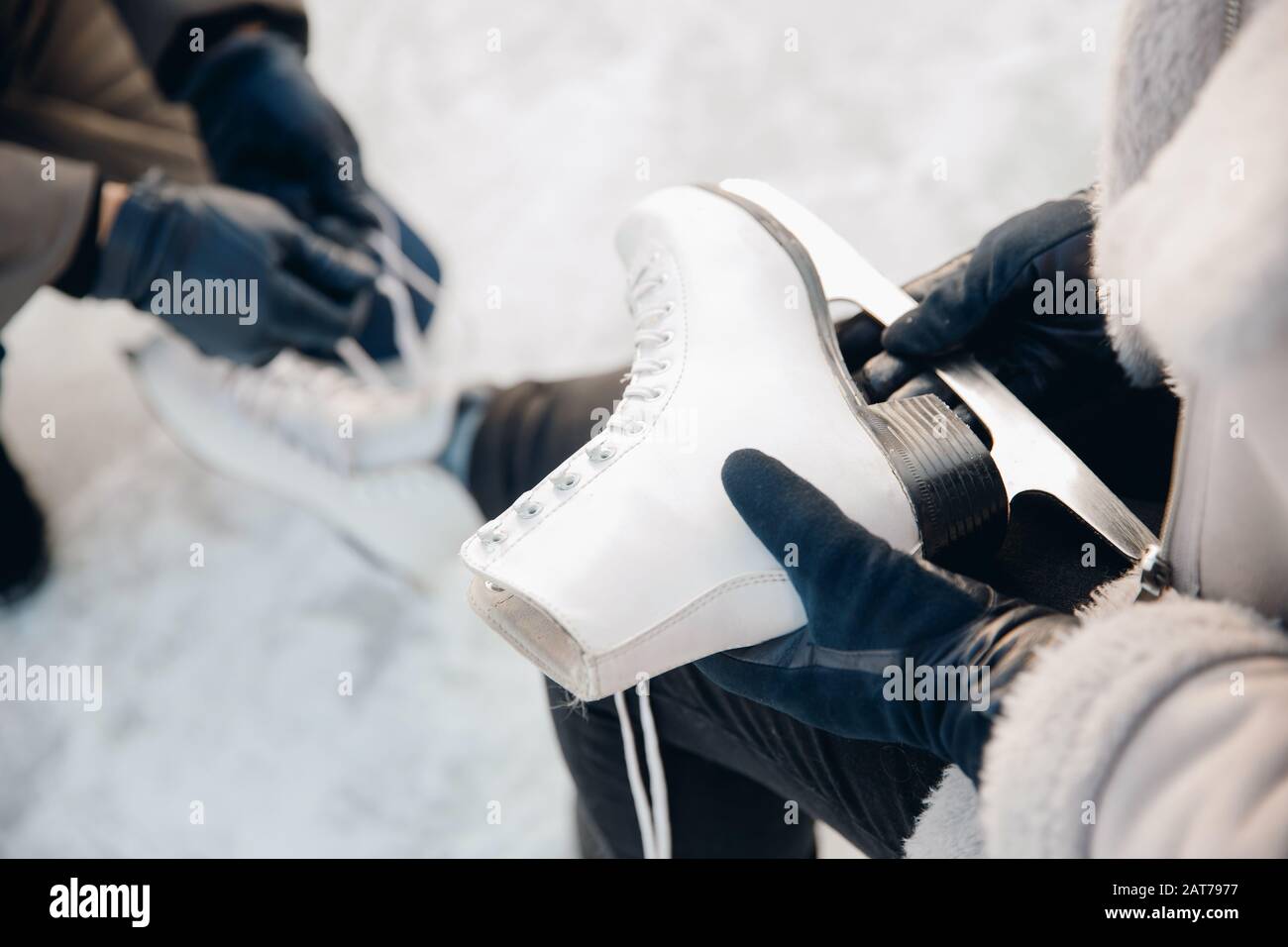 El hombre ayuda a poner en patines para pista de hielo de nieve a la niña, concepto de vacaciones de invierno, descanso familiar Foto de stock