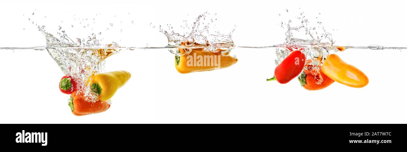 El pimentón en rojo, orage y amarillo cae en el agua Foto de stock