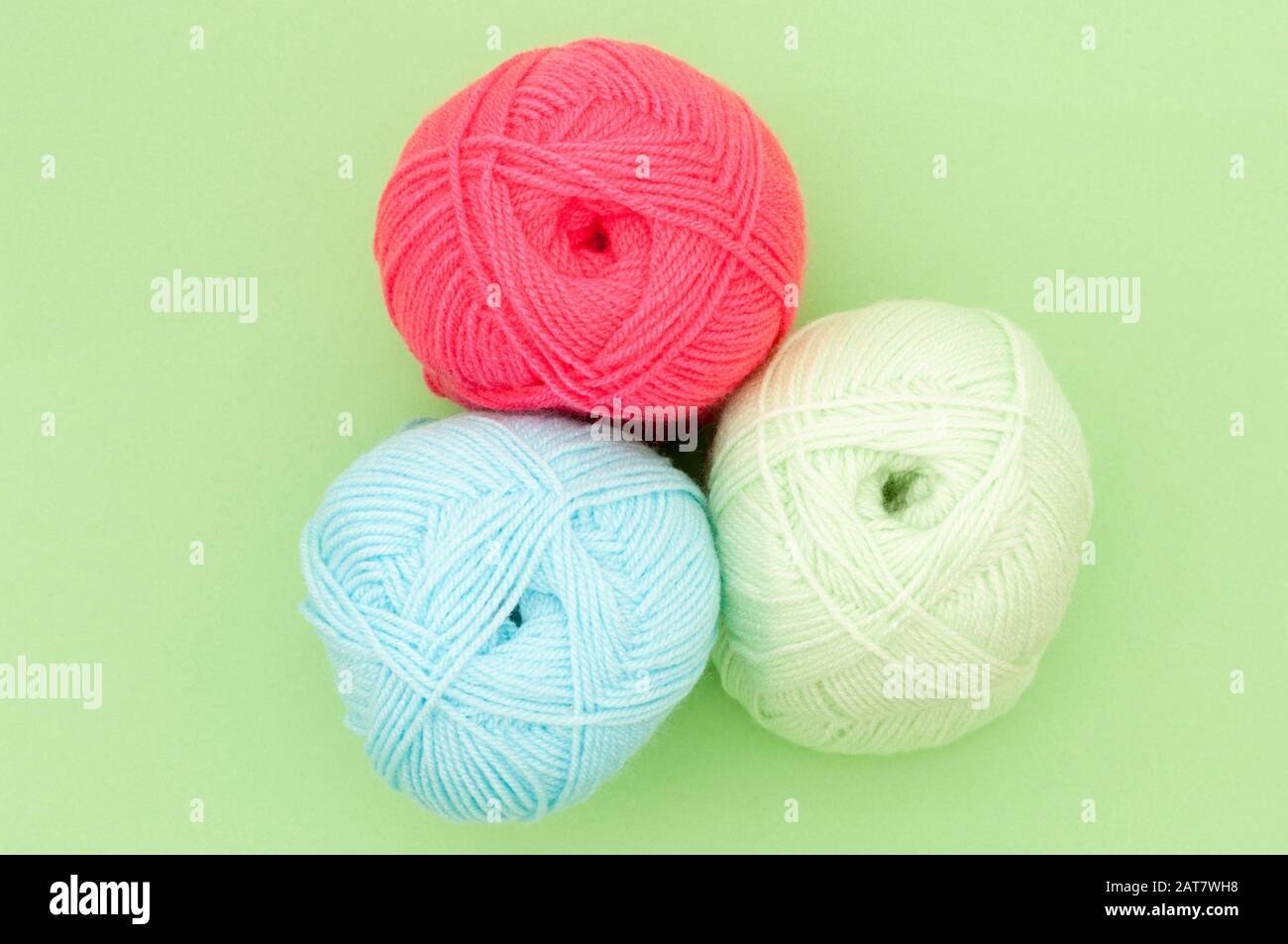 Tres bolas de lana de color sobre fondo verde Foto de stock