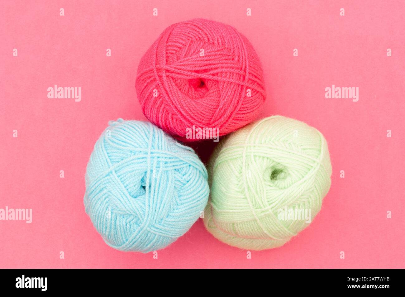Tres bolas de lana de color sobre fondo rosa Foto de stock