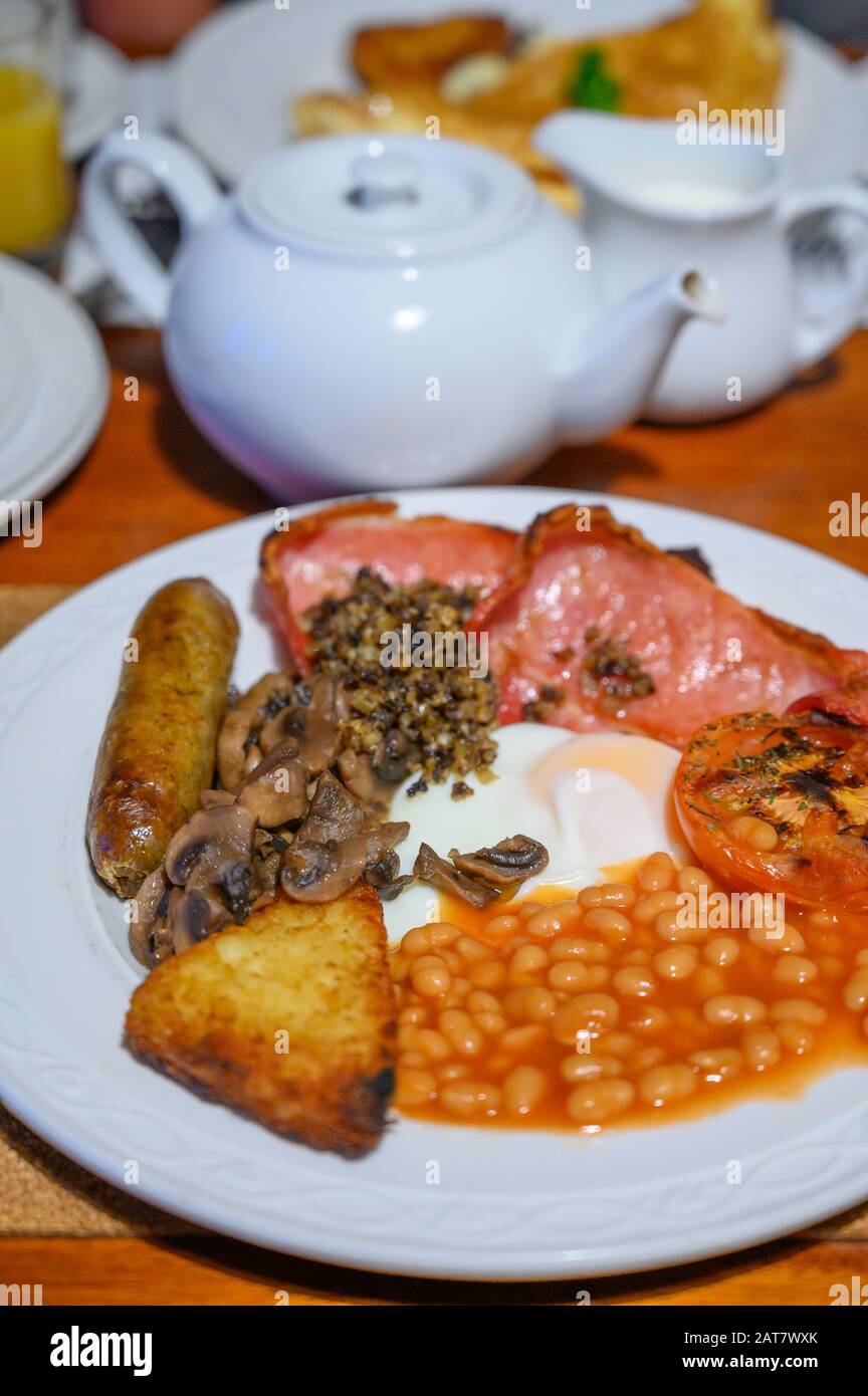 Pizarra blanca con desayuno escocés completo con tocino, huevo frito, frijoles, tomate, salchichas asadas, pudín, croquetas de patata y haggis Foto de stock