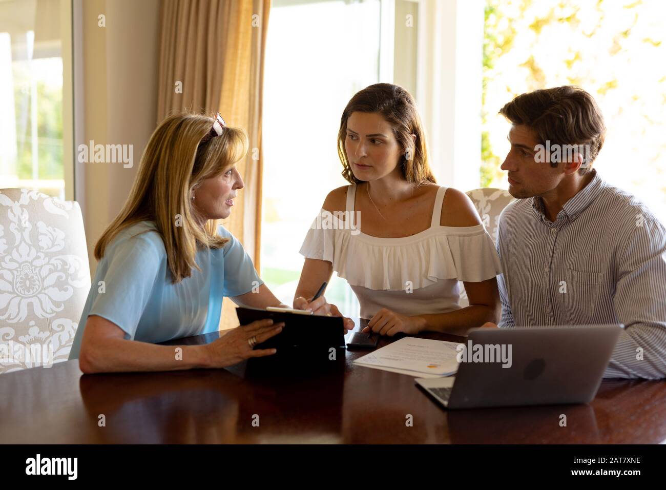 Una pareja joven que habla con un asesor financiero en casa Foto de stock