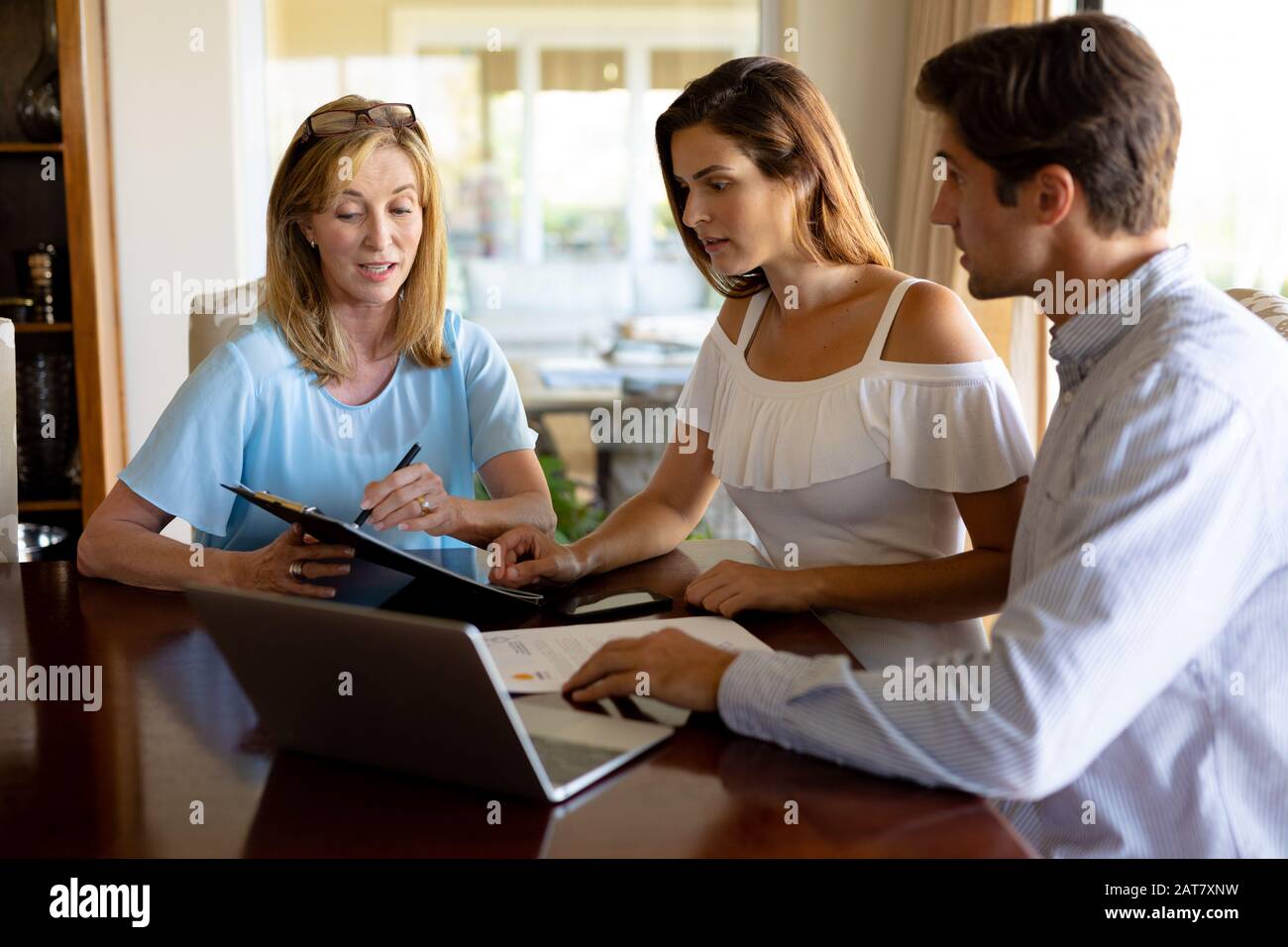 Una pareja joven que habla con un asesor financiero en casa Foto de stock