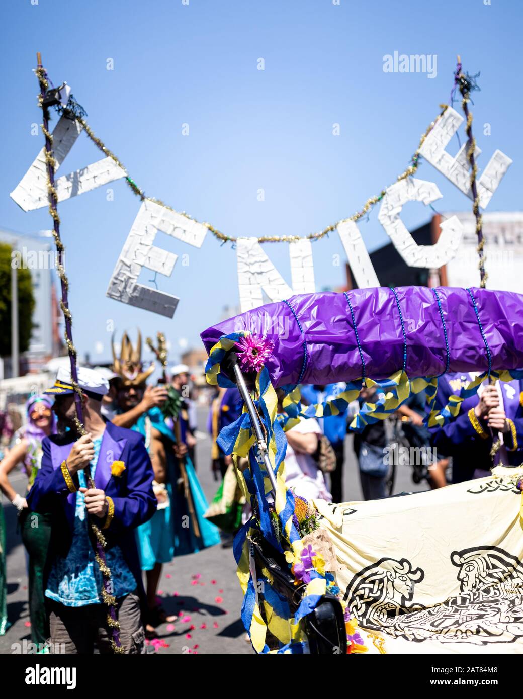 Desfile festivo con Mucha Gente con ropa colorida sosteniendo un cartel de Venecia. Esta procesión de vacaciones está llena de celebración y colores vibrantes. Foto de stock