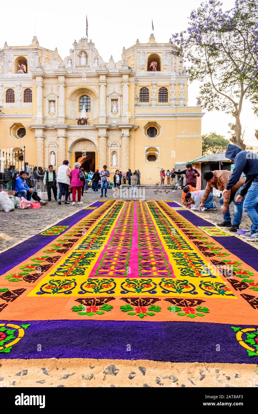 Antigua, Guatemala - 14 de abril de 2019: Fabricación de aserrín teñidos alfombra de la procesión del domingo de palma por la iglesia de la Merced en el lugar declarado Patrimonio de la Humanidad por la UNESCO. Foto de stock