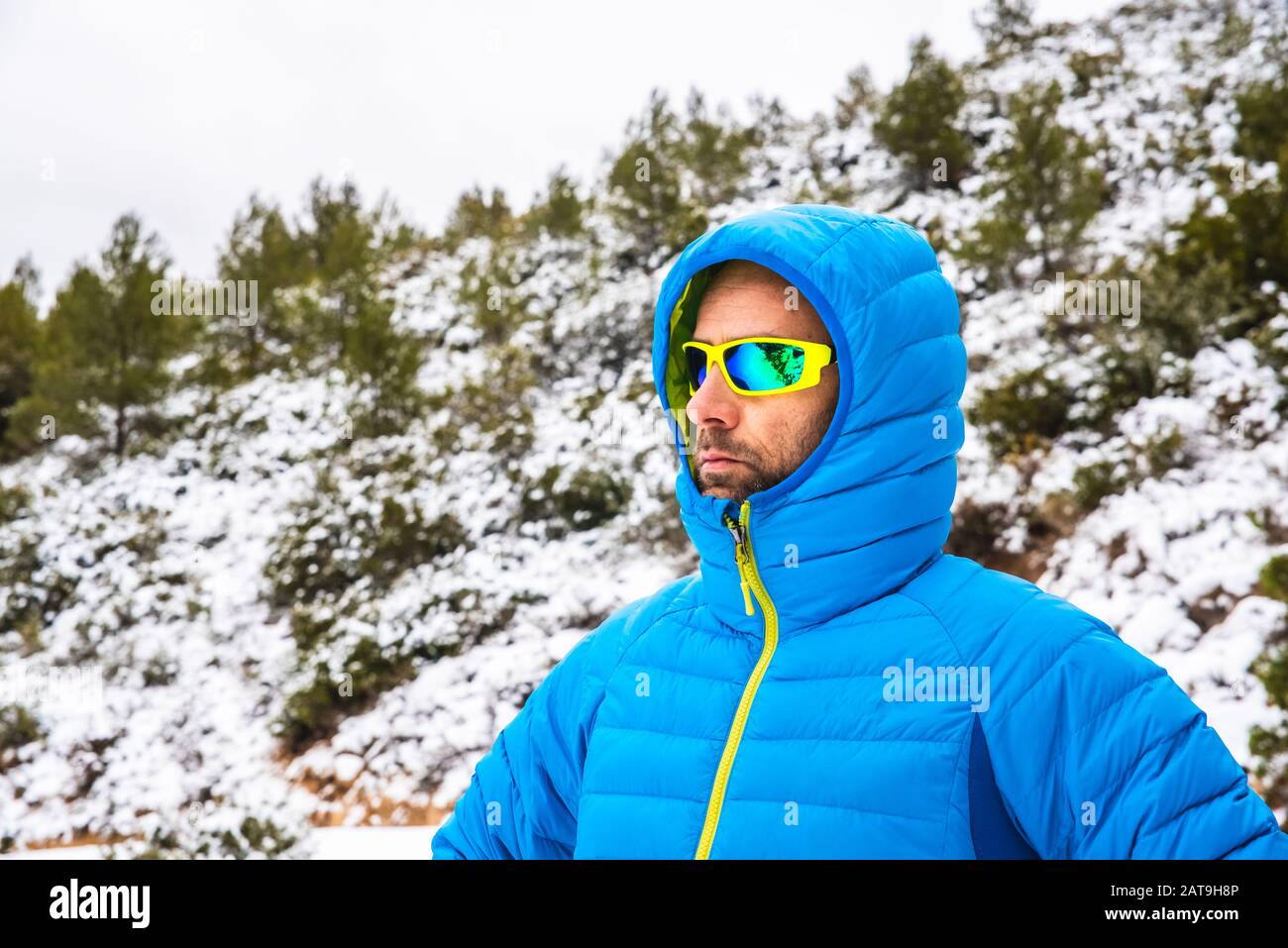 Hombre montañero abrigo azul y gafas de sol caminando en un sendero nevado de montaña en tiempo libre Fotografía de stock - Alamy
