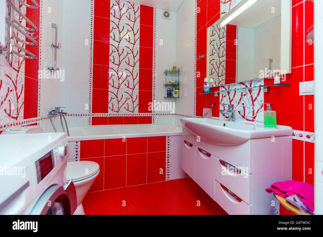 Cuarto de baño en un pequeño apartamento. Baldosas con motivos florales  rojos y blancos. En la foto se puede ver: Inodoro, bañera, lavabo, espejo  Fotografía de stock - Alamy