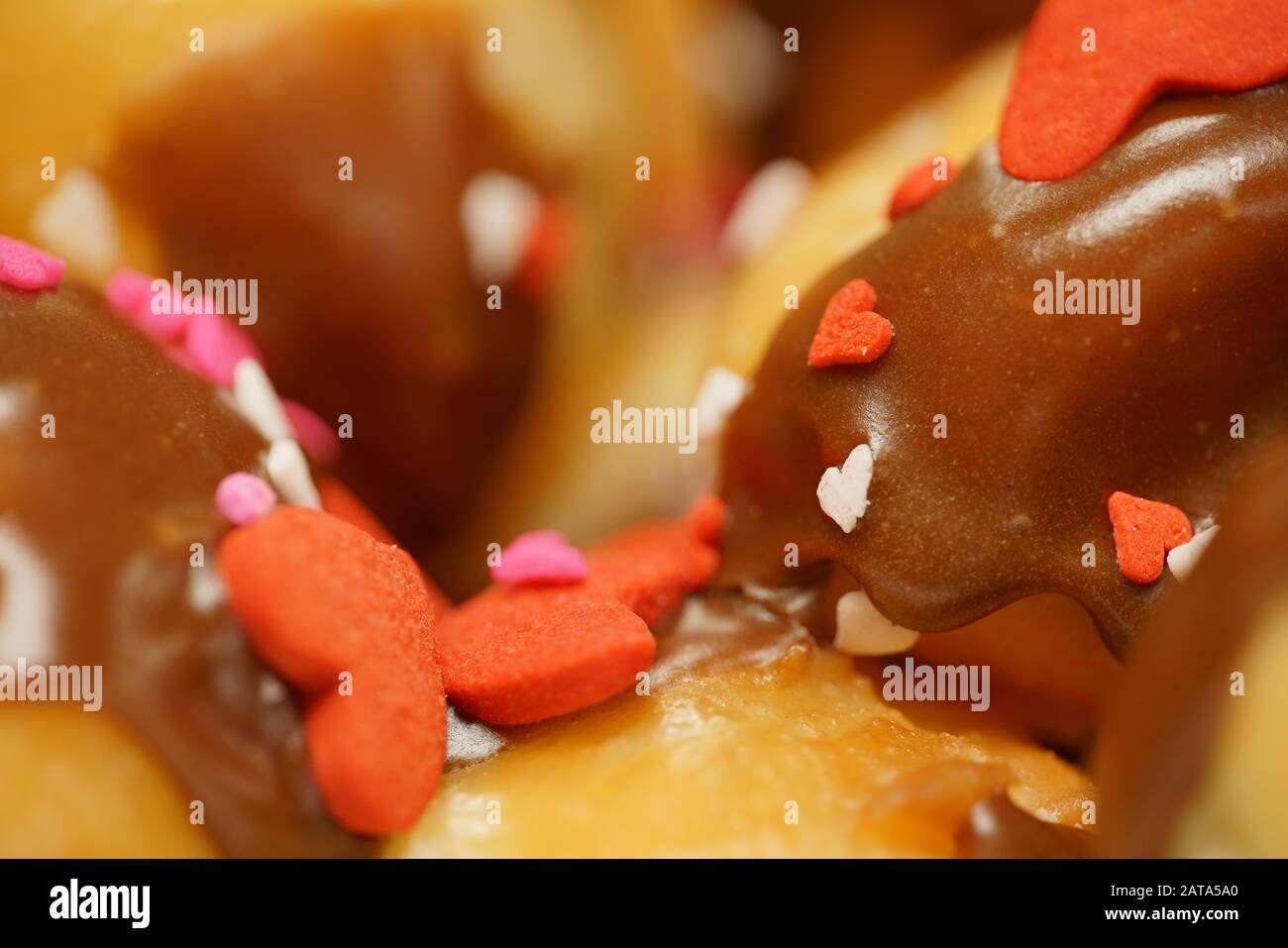 Rosquillas con glaseado de chocolate y el corazón de San Valentín espolvorea Foto de stock