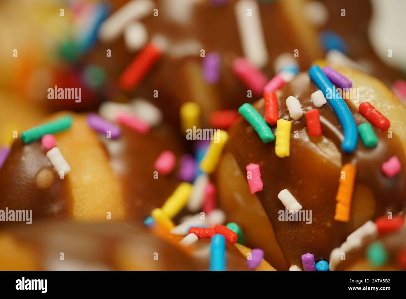 Rosquillas con hielo de chocolate y rociadas de arco iris Foto de stock
