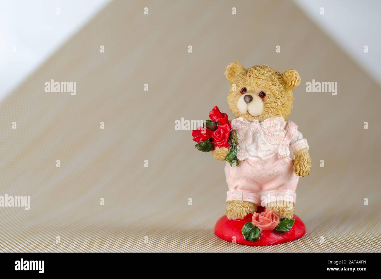 Un pequeño oso de peluche lindo sostiene en su pata un ramo de flores para  su amado. Espacio libre para texto a la izquierda. Captura a nivel de ojos.  Enfoque selectivo Fotografía