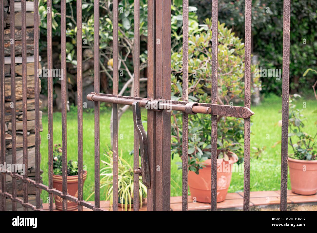 Puerta metálica con puertas que tienen un cierre de hierro con barra  deslizante y de bloqueo y barras verticales oxidadas por el paso del tiempo  Fotografía de stock - Alamy