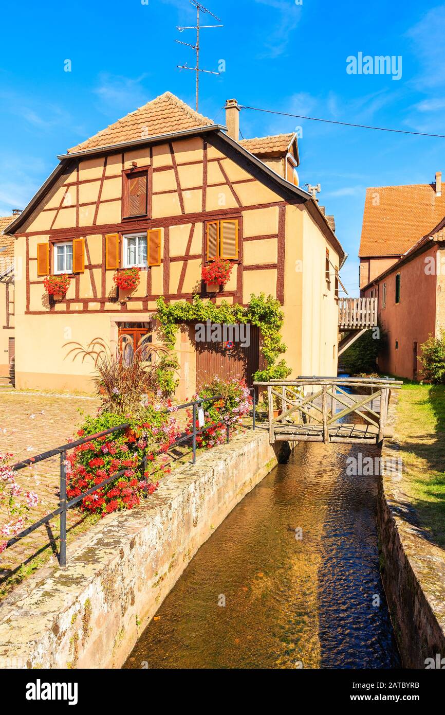 Hermosa casa de colores tradicionales a lo largo del canal en el pintoresco pueblo Kientzheim, región vinícola de Alsacia, Francia Foto de stock