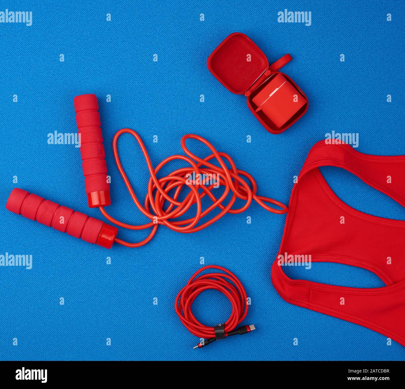 camiseta deportiva roja, cable de salto rojo y auriculares inalámbricos en  un estuche rojo sobre fondo azul, vista superior, plano Fotografía de stock  - Alamy