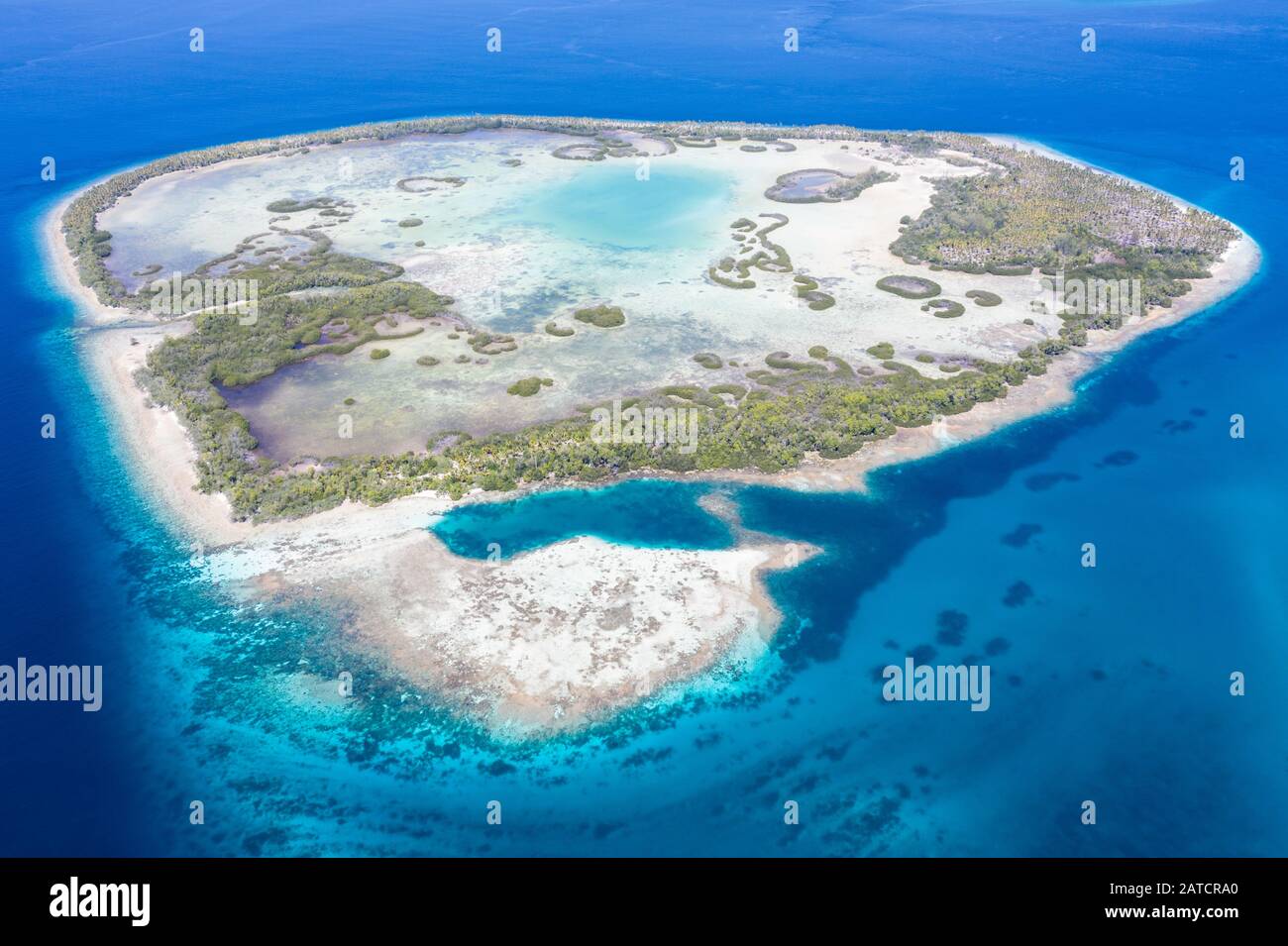 Una remota isla tropical en el Mar de Molucca está rodeada por un bosque de manglares que rodea una laguna poco profunda. Esta isla se encuentra en medio del Triángulo del Coral. Foto de stock