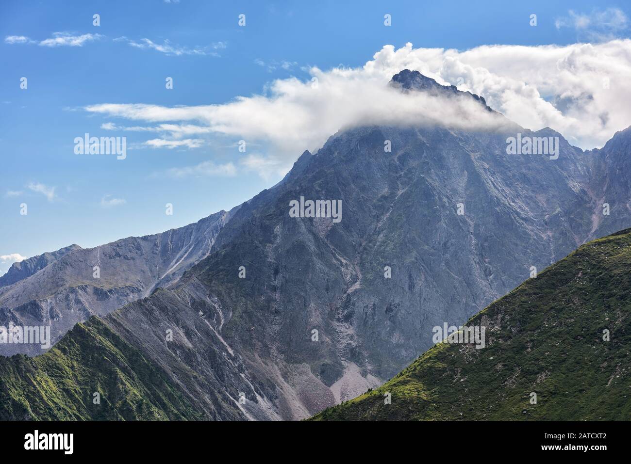Nubes blancas atrapadas en el pico. Montañas de Sayan. Siberia Oriental. Rusia Foto de stock