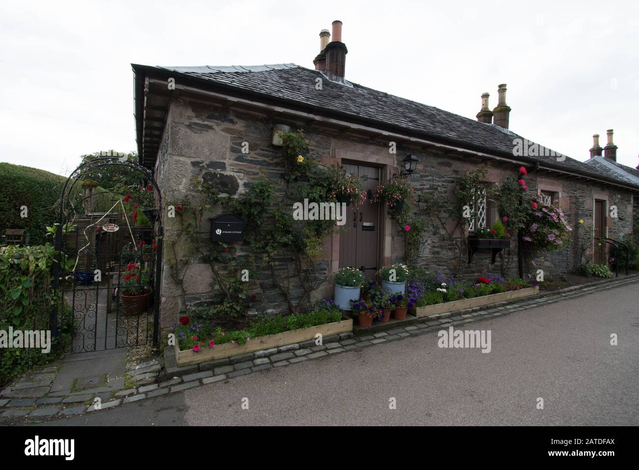 Bonita casa de piedra con canastas colgantes y flores en Luss, Escocia  Fotografía de stock - Alamy