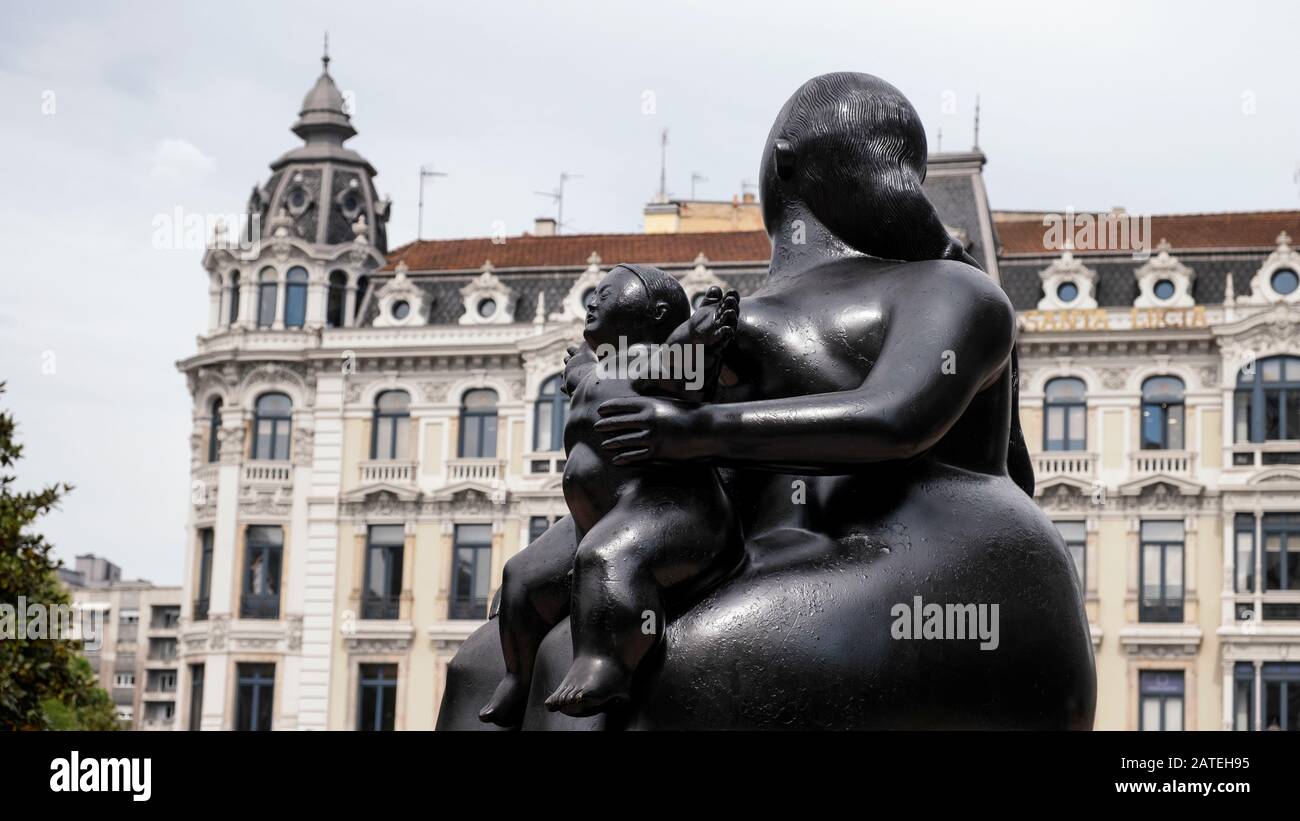 Escultura en bronce la Maternidad del artista Fernando Botero en Plaza de la Escandalera con el edificio Casa Conde en la parte trasera (Oviedo, Asturias, España) Foto de stock