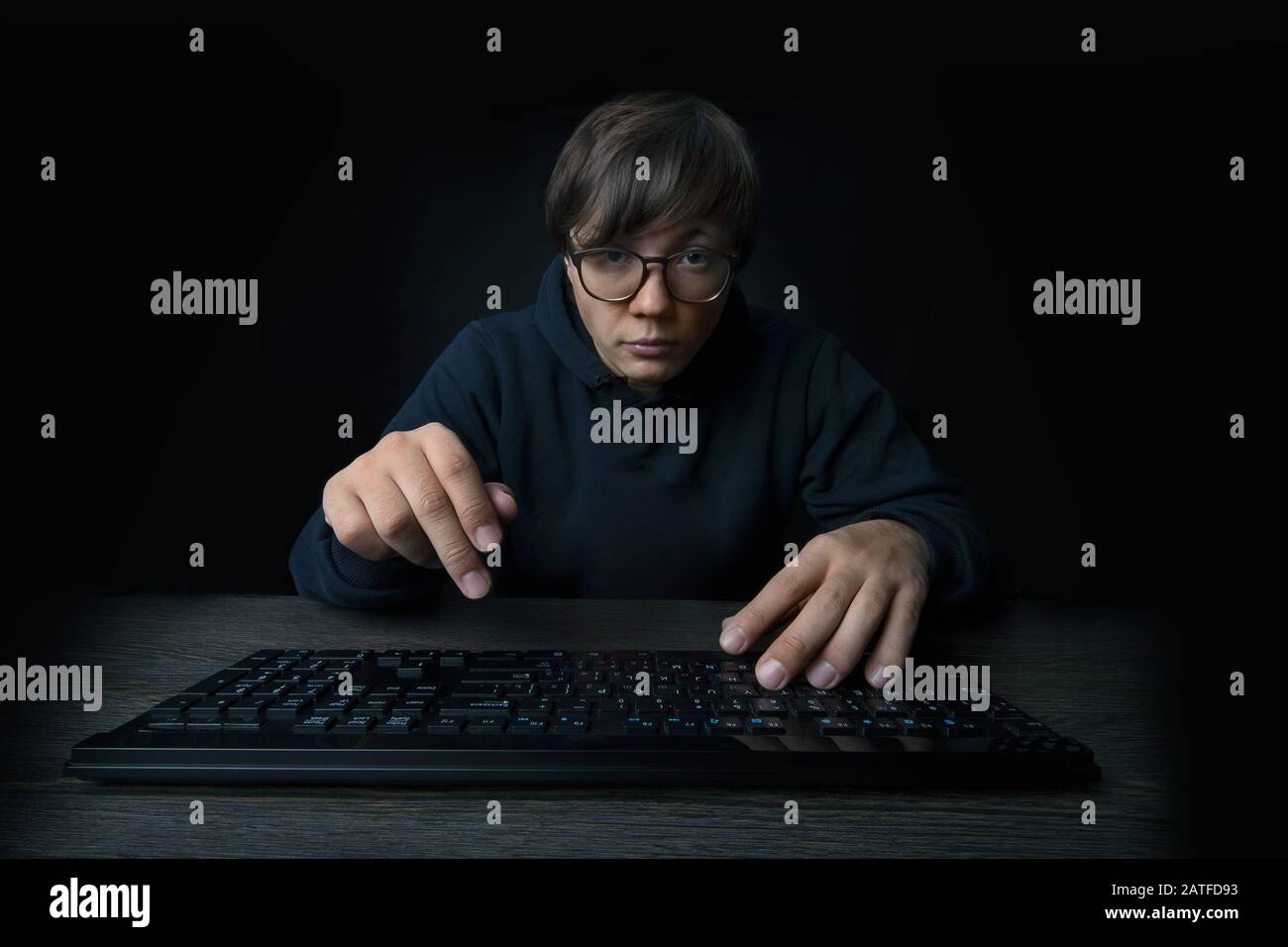 el programador hombre sostiene las manos sobre el teclado y mira la cámara,  sobre fondo oscuro Fotografía de stock - Alamy