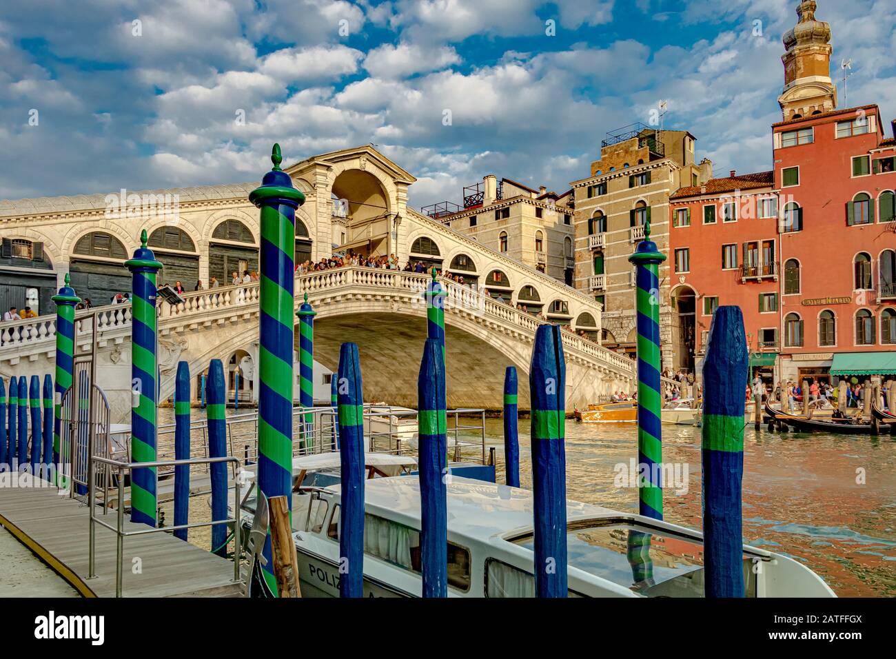 Multitudes en el puente Rialto, el puente más antiguo que cruza el Gran Canal de Venecia en primer plano, postes de madera rayados o Pali da casada Foto de stock
