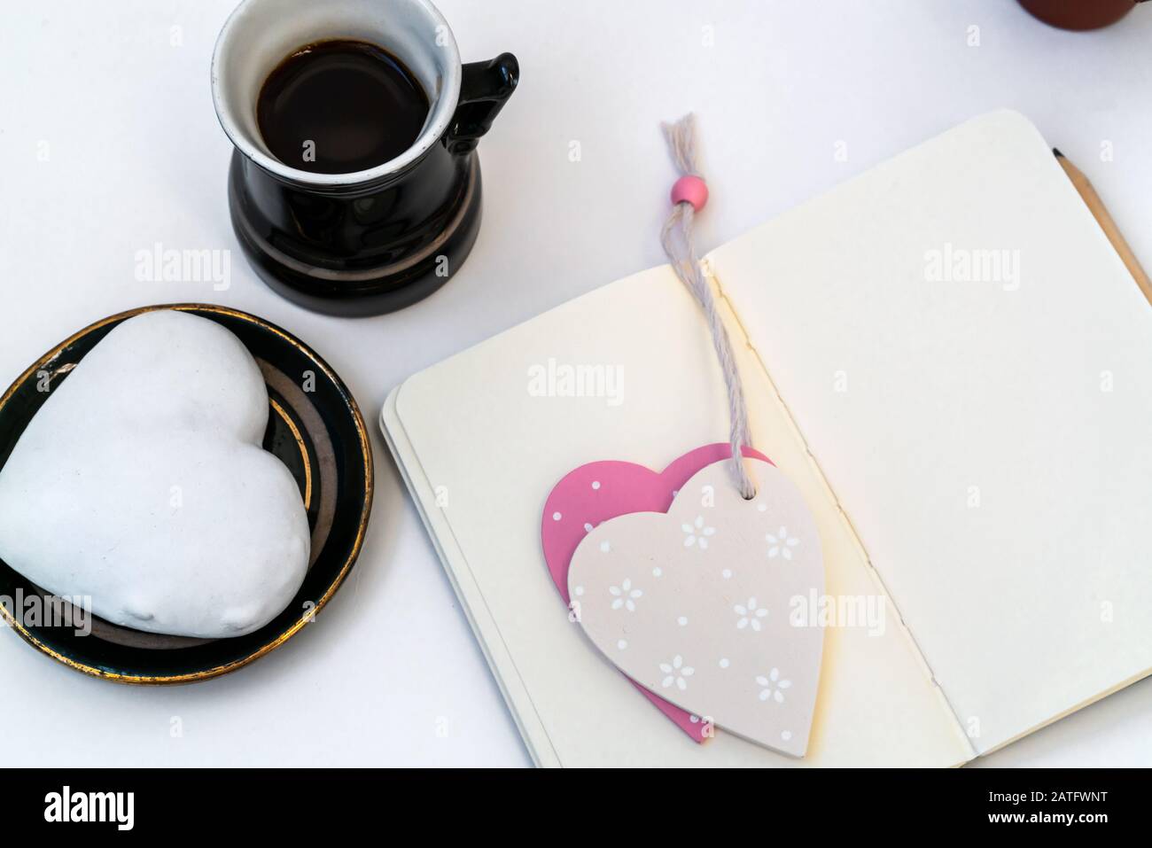 Composición del día de San Valentín. Escritorio femenino con taza de café y plato con galleta de jengibre en forma de corazón sobre fondo blanco. Concepto de celebración del día de San Valentín Foto de stock
