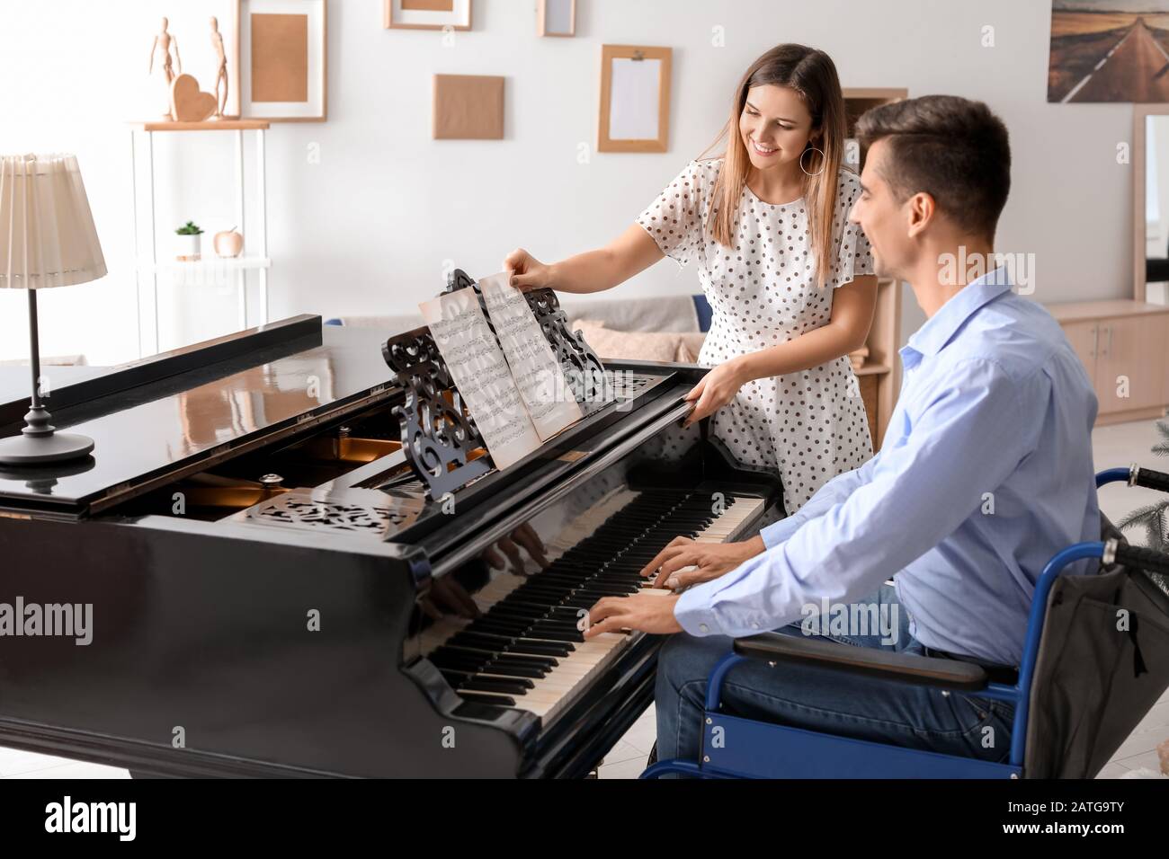 Mujer enseñando a un joven en silla de ruedas a tocar piano Foto de stock