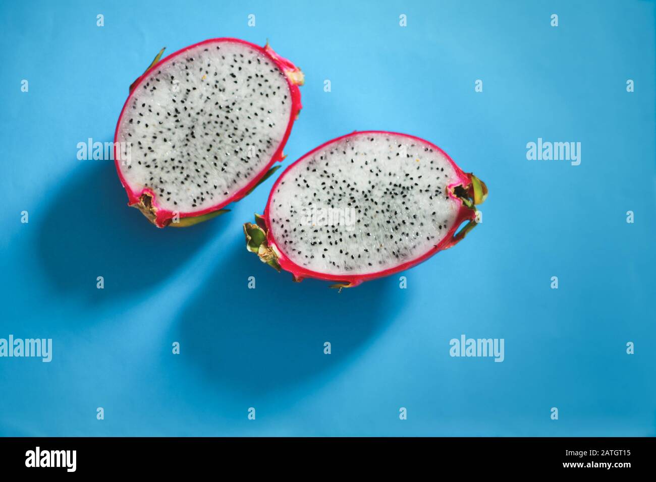 Fruta de libélula fresca cortada en rodajas o pitaya sobre un fondo azul brillante para mostrar contraste de colores, concepto de diversión, verano y cultura pop Foto de stock