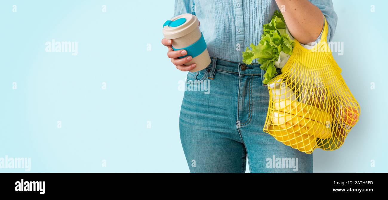 Compras sin residuos: Mujer con bolsa de compra reutilizable amarilla y taza de café sobre fondo brillante Foto de stock