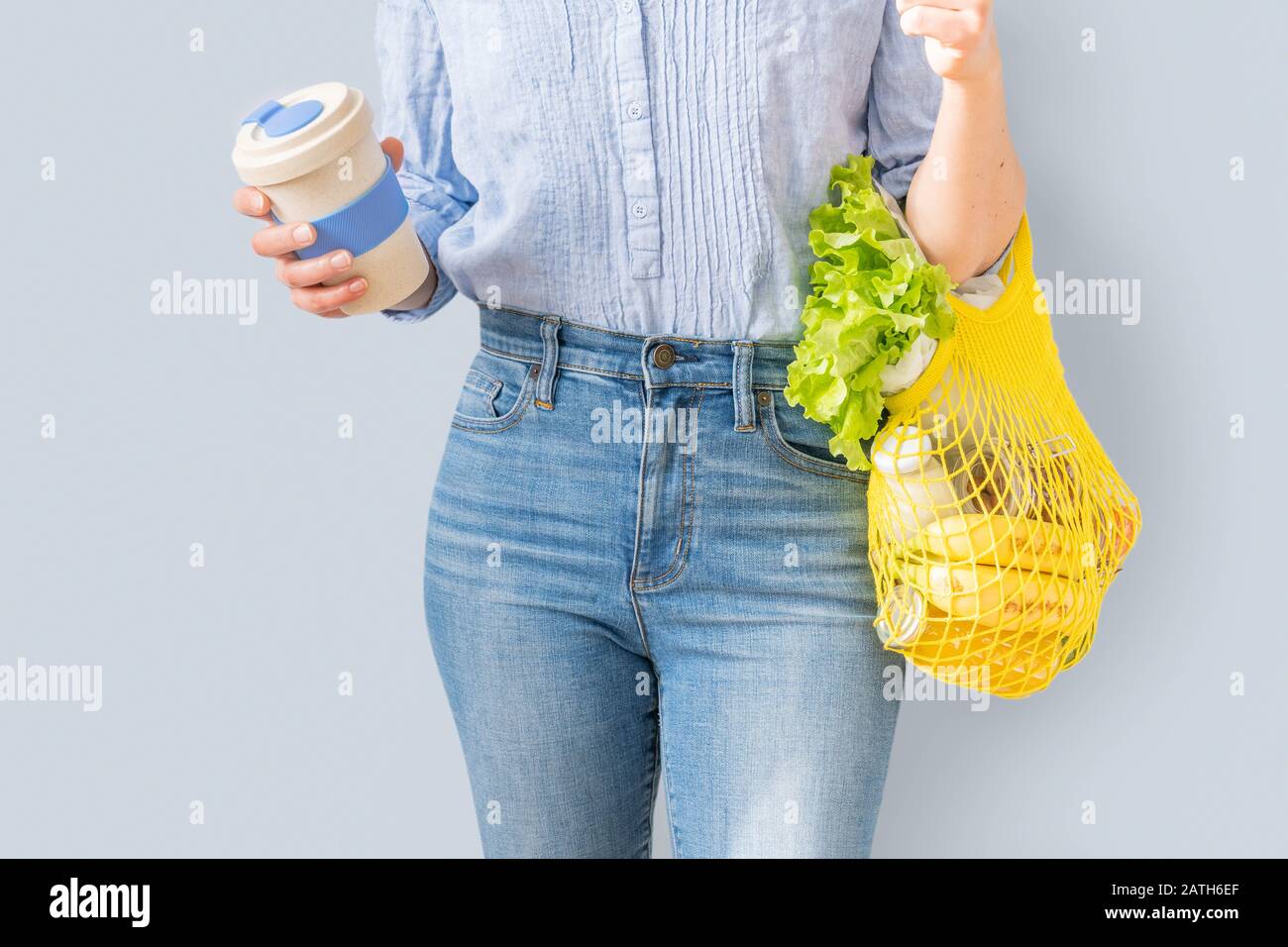 Compras sin residuos: Mujer con bolsa de compra reutilizable amarilla y taza de café sobre fondo brillante Foto de stock