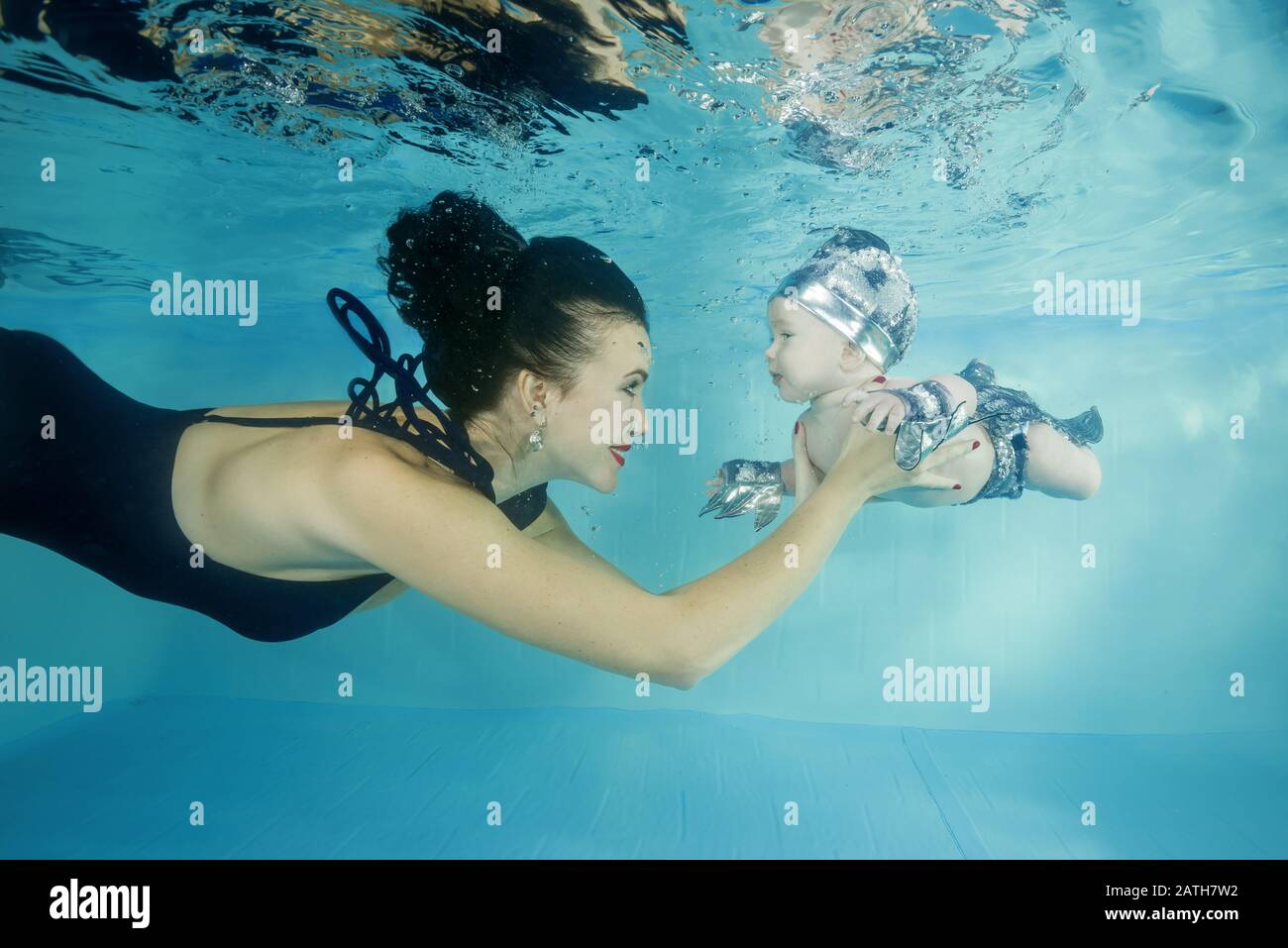 Mamá con un pequeño hijo sonriendo inmersiones bajo el agua en una piscina Foto de stock